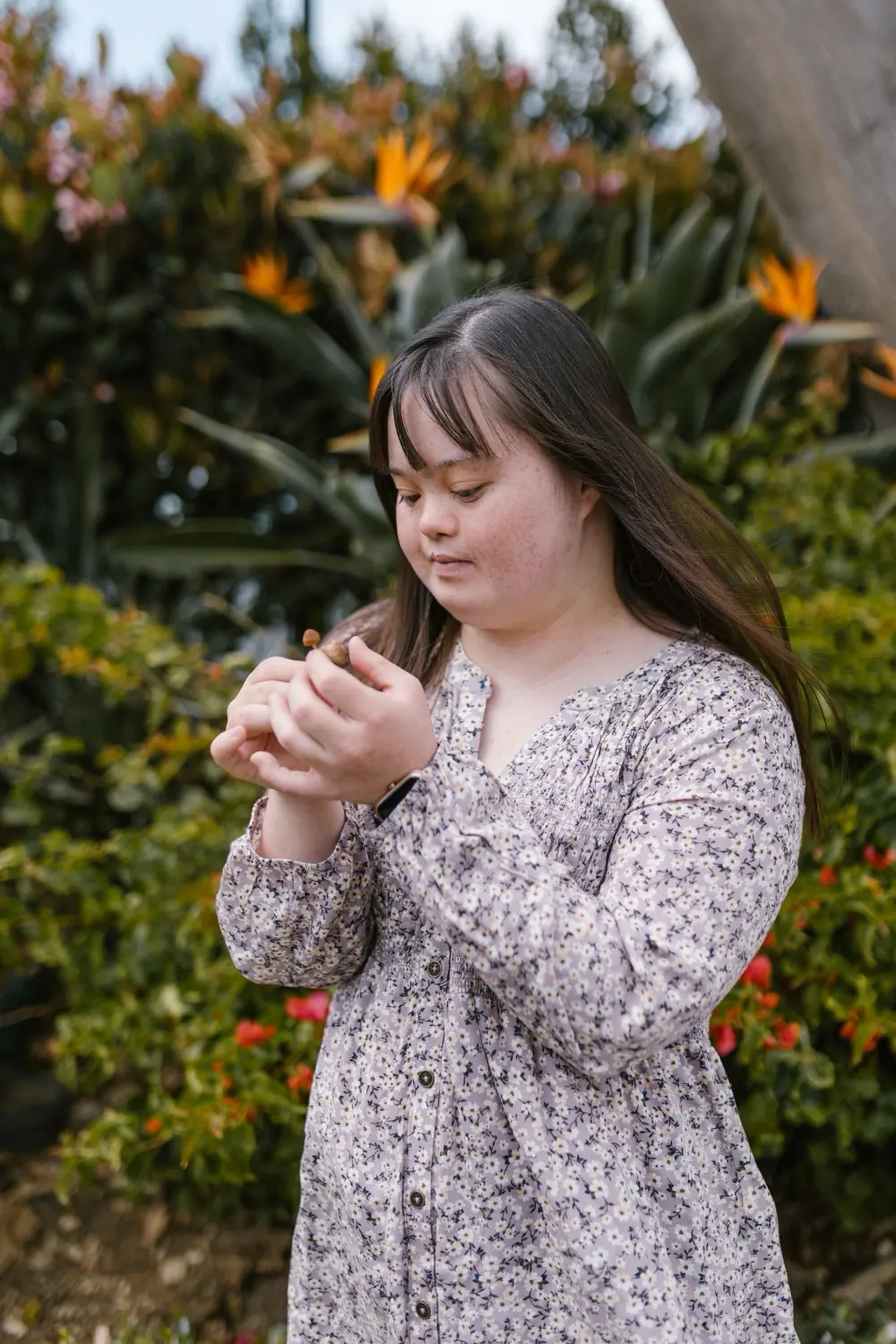 A young woman with Down syndrome in a garden of flowers, a quiet moment in the sun.