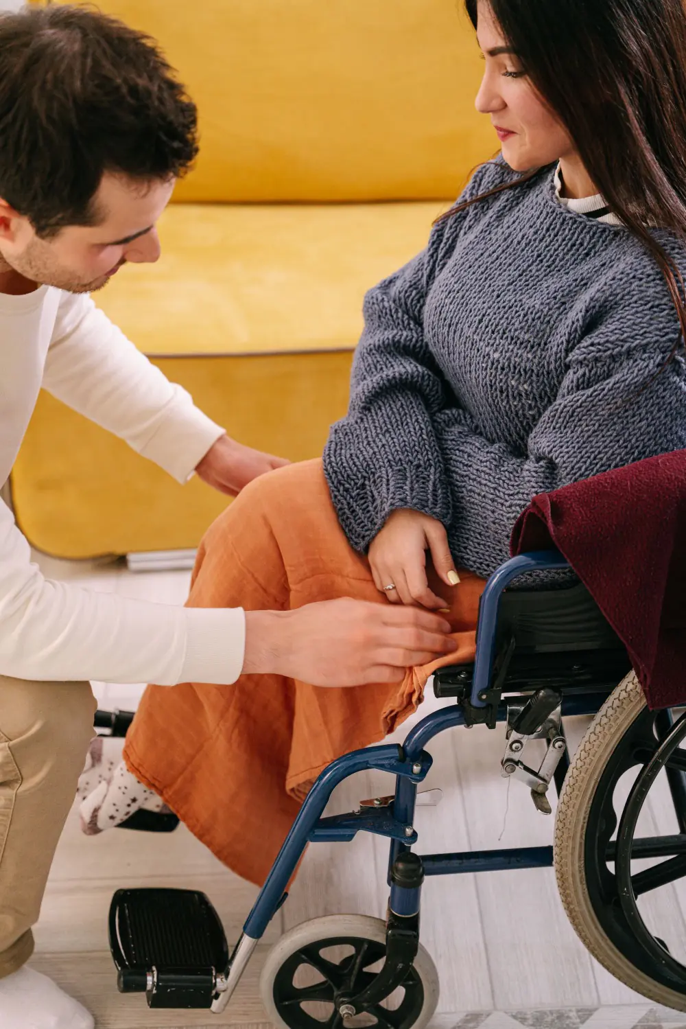 A support worker's hands resting gently alongside a person seated in a wheelchair.