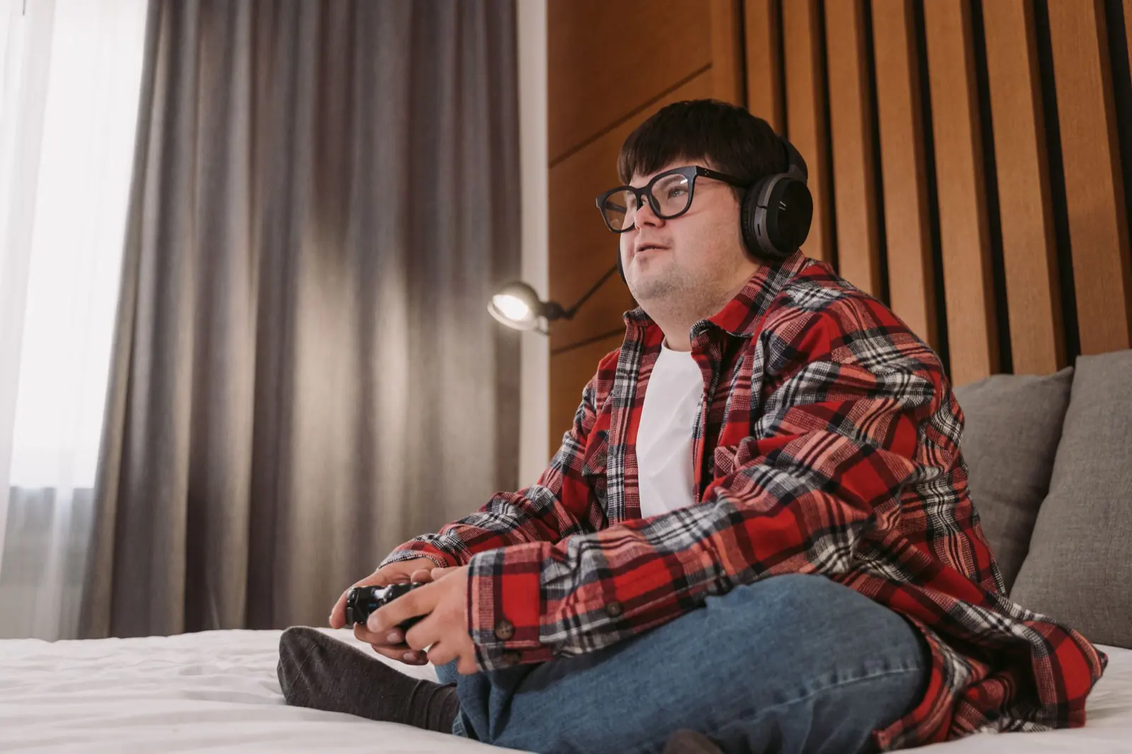 A young man relaxing at home with headphones and a handheld game.